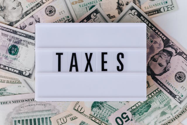a board with the word taxes resting on a bunch of cash